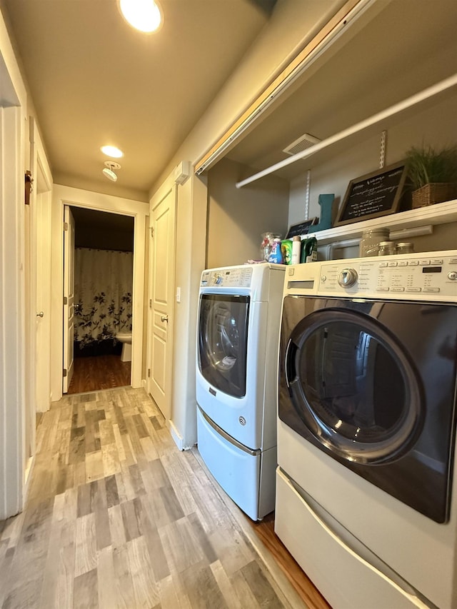 washroom with laundry area, washer and dryer, and wood finished floors