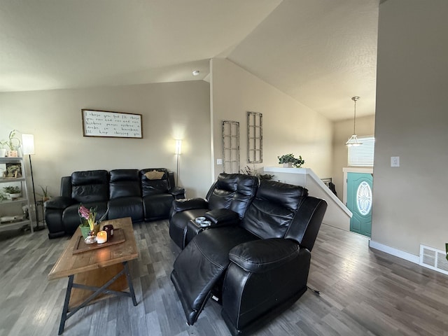 living room featuring lofted ceiling, baseboards, visible vents, and wood finished floors