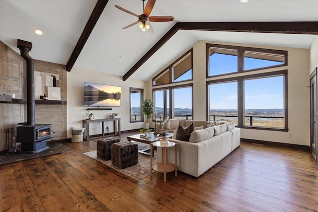 living room with beam ceiling, a wood stove, wood finished floors, high vaulted ceiling, and baseboards