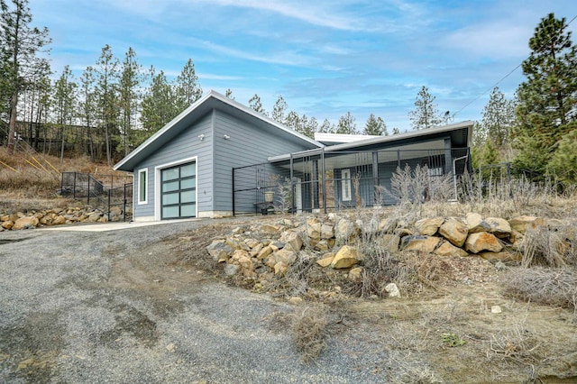 view of front of property featuring a garage, dirt driveway, and fence