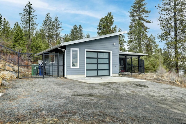 garage featuring a carport, gravel driveway, and fence