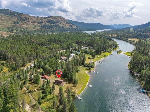 drone / aerial view featuring a wooded view and a water and mountain view