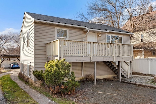 back of property featuring fence, driveway, stairway, a wooden deck, and a carport