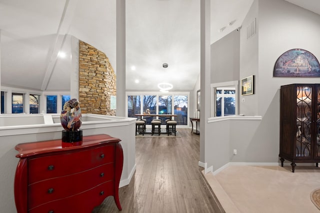 hall featuring high vaulted ceiling, wood-type flooring, and baseboards