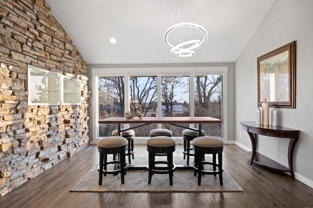 dining space featuring a notable chandelier, baseboards, vaulted ceiling, and wood finished floors