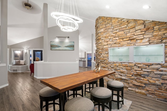 dining room with lofted ceiling, wood finished floors, visible vents, and a notable chandelier