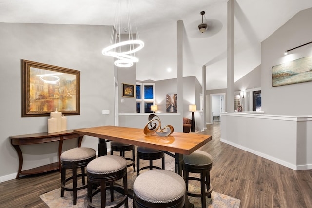 dining area featuring a chandelier, lofted ceiling, baseboards, and wood finished floors