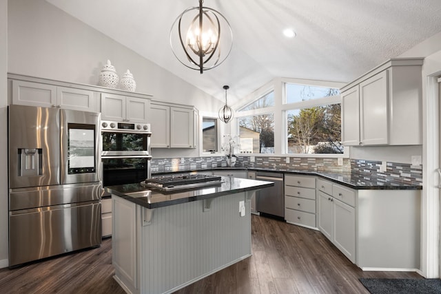 kitchen with a chandelier, appliances with stainless steel finishes, vaulted ceiling, and dark wood finished floors