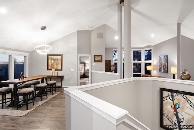 interior space featuring pendant lighting, high vaulted ceiling, wood finished floors, visible vents, and an inviting chandelier