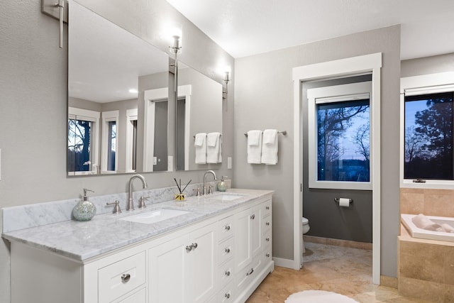 bathroom with a bath, double vanity, a sink, and toilet