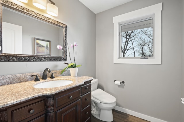 bathroom with baseboards, vanity, toilet, and wood finished floors