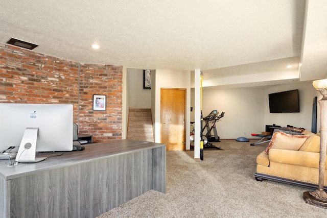 office featuring carpet, visible vents, a textured ceiling, and brick wall