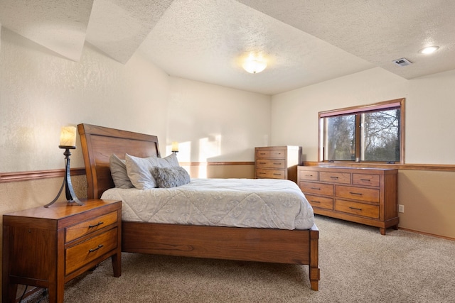 bedroom featuring light carpet, visible vents, and a textured ceiling