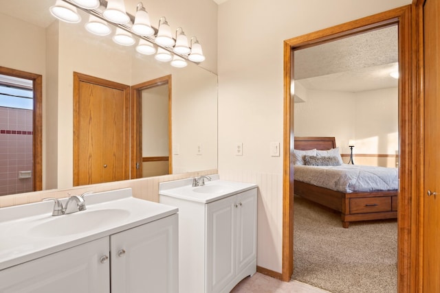 ensuite bathroom with a textured ceiling, two vanities, a sink, and ensuite bathroom