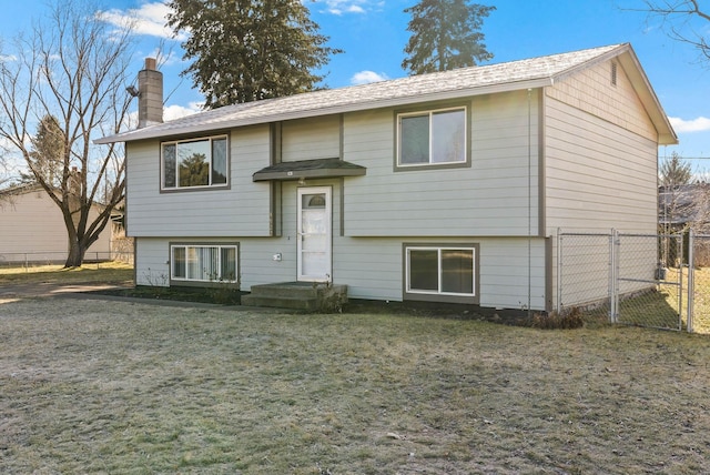 bi-level home featuring a gate, a chimney, fence, and a front lawn