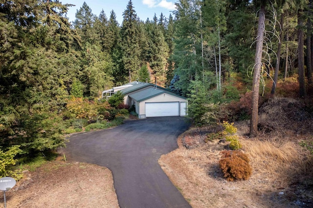 garage with driveway and a view of trees