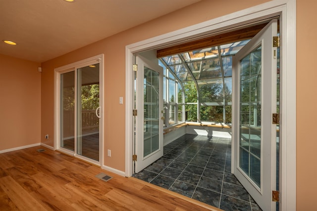 doorway with recessed lighting, wood finished floors, visible vents, a sunroom, and baseboards