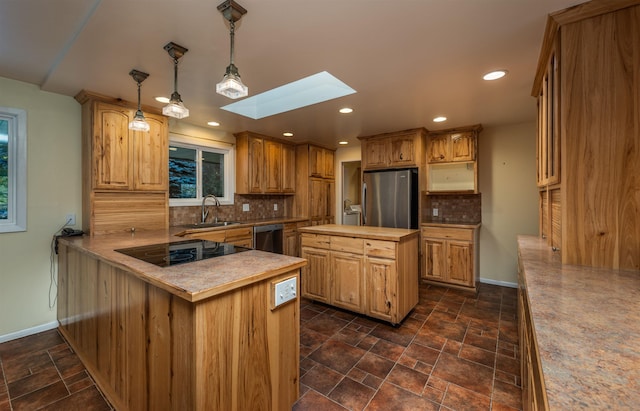 kitchen featuring a skylight, stainless steel appliances, backsplash, a sink, and baseboards