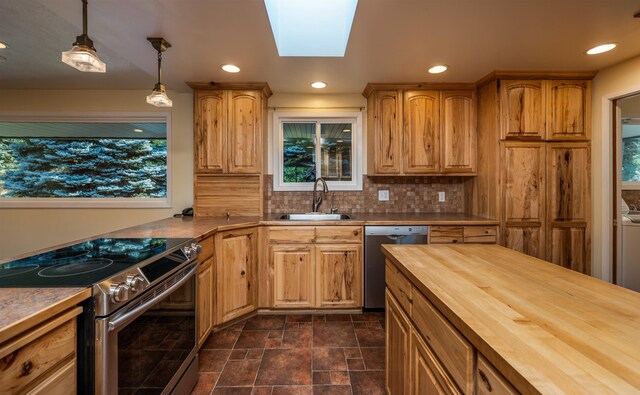 kitchen with a skylight, decorative backsplash, butcher block counters, stainless steel appliances, and a sink