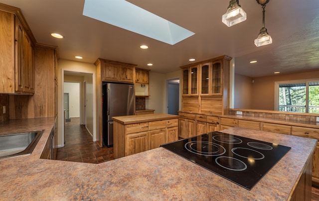 kitchen with recessed lighting, black cooktop, a skylight, a kitchen island, and freestanding refrigerator