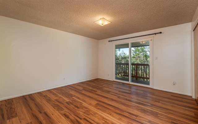 spare room featuring a textured ceiling, wood finished floors, and baseboards