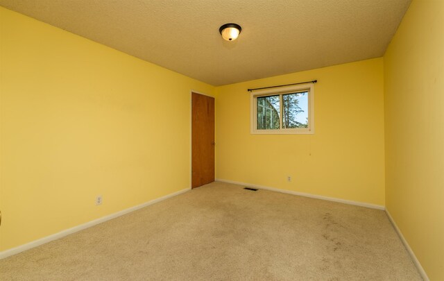 unfurnished room featuring light carpet, baseboards, visible vents, and a textured ceiling