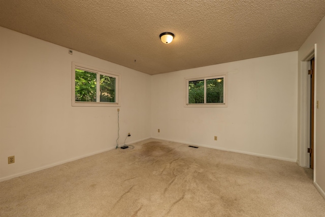 carpeted empty room featuring a healthy amount of sunlight, visible vents, and baseboards