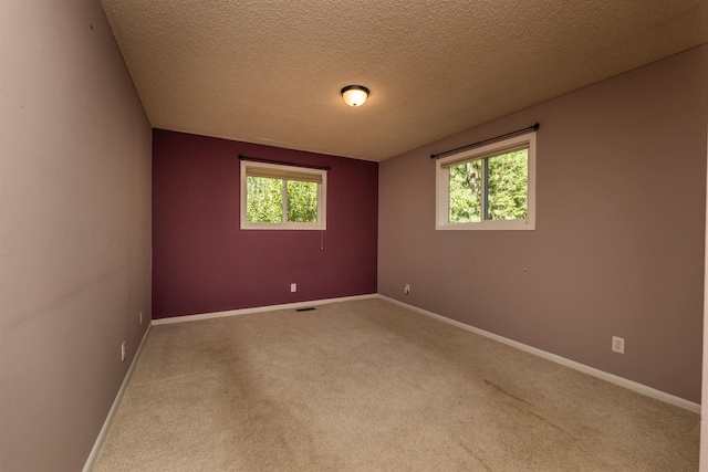 unfurnished room with carpet floors, a wealth of natural light, visible vents, and baseboards