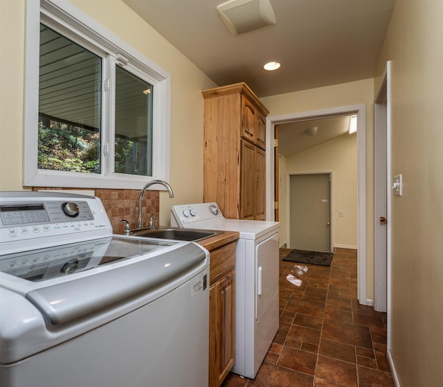 washroom featuring cabinet space, baseboards, visible vents, washer and dryer, and a sink