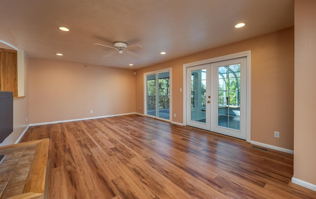 unfurnished living room with baseboards, visible vents, wood finished floors, french doors, and recessed lighting