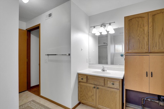 bathroom with baseboards, an enclosed shower, visible vents, and vanity