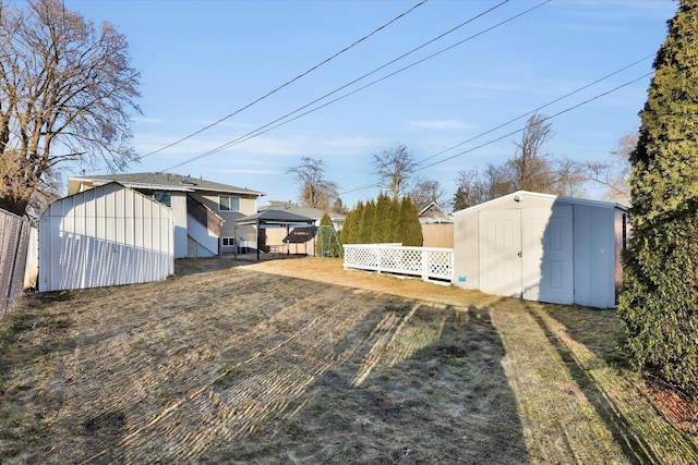 view of yard featuring an outbuilding, fence, and a storage shed