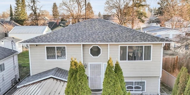 split foyer home with a shingled roof and fence