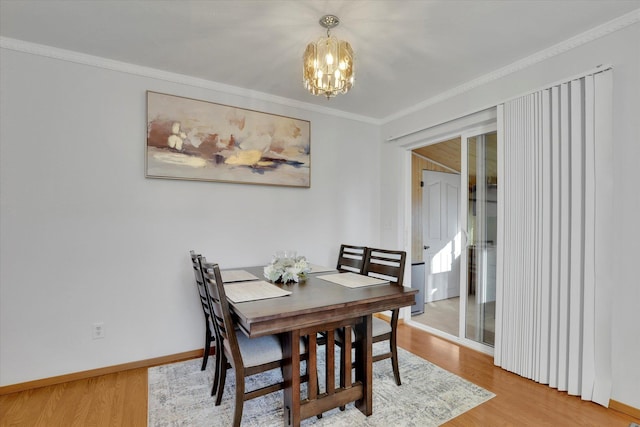 dining space featuring baseboards, ornamental molding, wood finished floors, and a notable chandelier