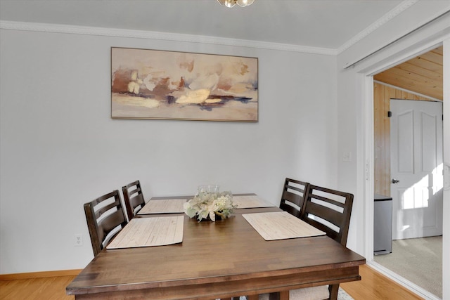 dining room featuring ornamental molding, baseboards, and wood finished floors