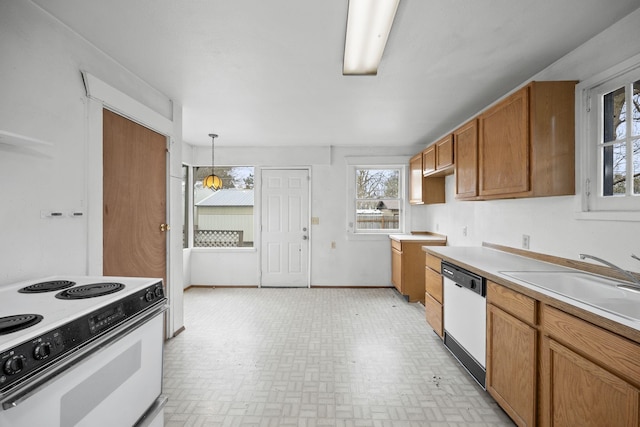 kitchen with white appliances, baseboards, brown cabinets, light countertops, and a sink