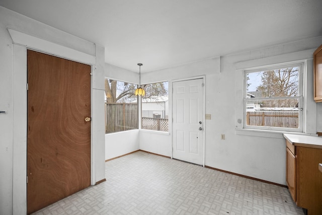 unfurnished dining area featuring light floors and baseboards