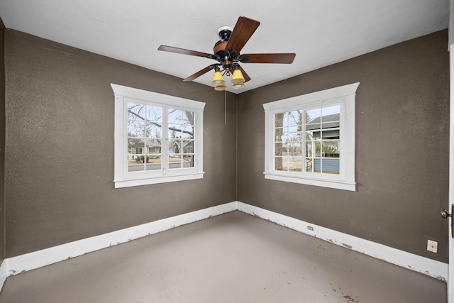 unfurnished room with ceiling fan, concrete floors, plenty of natural light, and baseboards