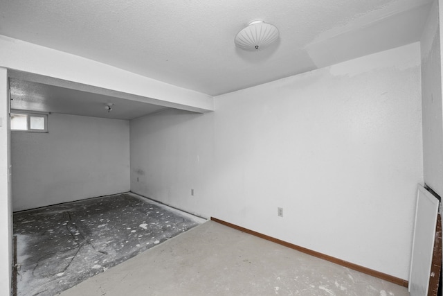 basement featuring baseboards and a textured ceiling