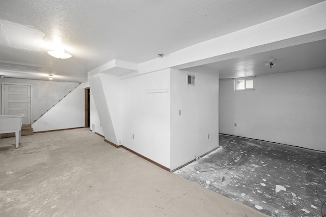 below grade area featuring stairs, visible vents, and a textured ceiling