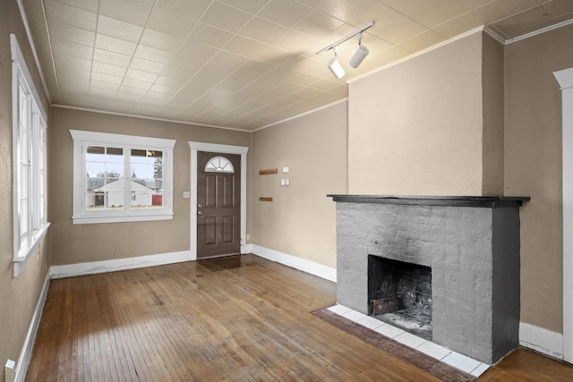 foyer entrance with a fireplace, ornamental molding, and hardwood / wood-style floors