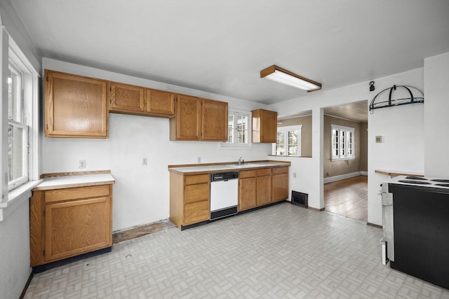 kitchen featuring light countertops, visible vents, brown cabinetry, white dishwasher, and black range with electric cooktop