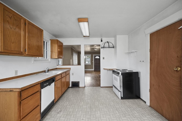 kitchen featuring brown cabinets, light countertops, visible vents, a sink, and white appliances