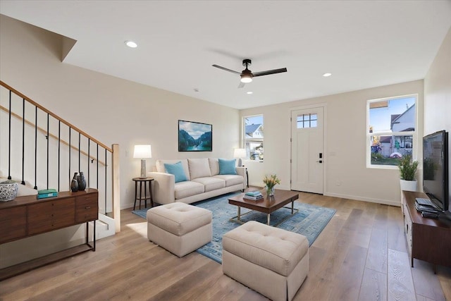 living area with a wealth of natural light, stairs, baseboards, and wood finished floors