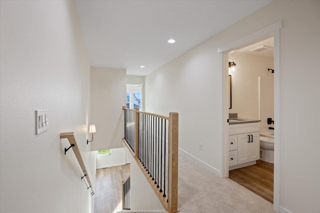 stairway featuring carpet, recessed lighting, visible vents, wood finished floors, and baseboards