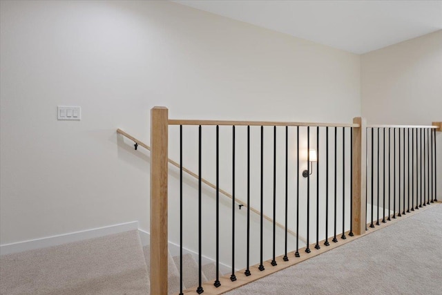 hallway with an upstairs landing, carpet, and baseboards