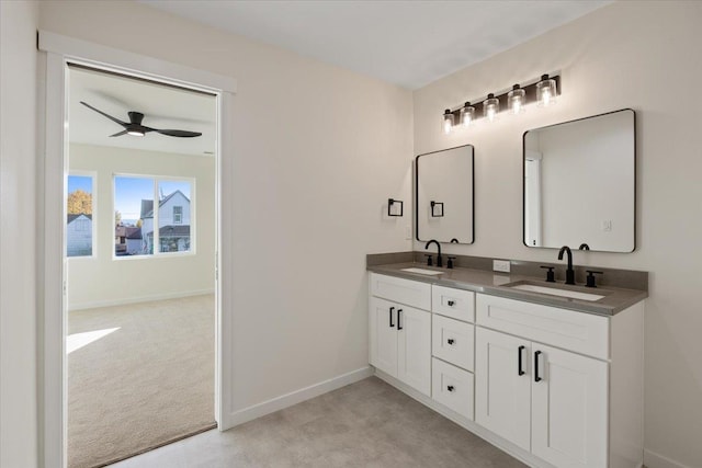 bathroom featuring ceiling fan, a sink, baseboards, and double vanity