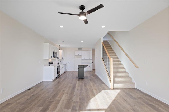 unfurnished living room with light wood finished floors, baseboards, ceiling fan, stairway, and recessed lighting