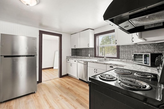 kitchen featuring under cabinet range hood, a sink, light wood-style floors, white cabinets, and appliances with stainless steel finishes