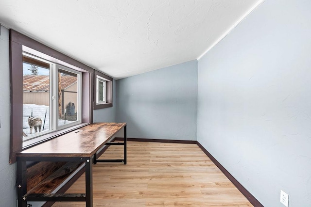 office with light wood-style floors, baseboards, and vaulted ceiling